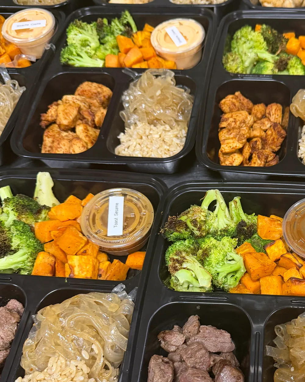 Brack's grain bowls with chicken, brown rice, roasted broccoli, sweet potatoes, and house sauces