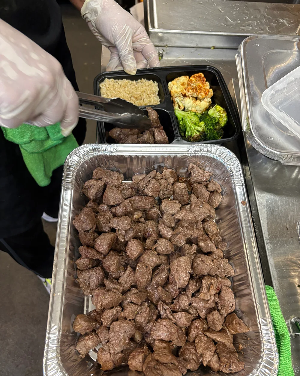 Seared steak bites in a catering tray with a Brack's bowl being assembled